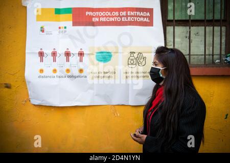 La Paz, Bolivie. 9 octobre 2020. Une femme participant à une simulation de vote attend en ligne à côté d'une affiche montrant les règles sanitaires à mettre en œuvre le jour du scrutin. L'élection se tiendra le 18 octobre 2020, presque exactement un an après la dernière controversée, ce qui a conduit à une grave crise politique en Bolivie et à la démission forcée de l'ancien président Evo Morales. Credit: Radoslaw Czajkowski/ Alamy Live News Banque D'Images