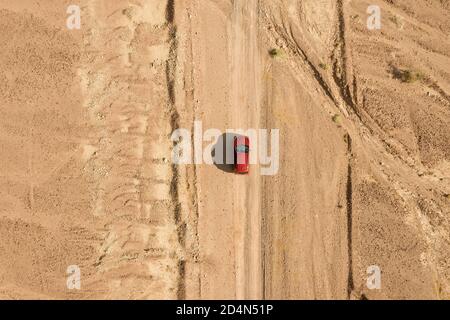 SUV rouge sur une trajectoire désertique, image aérienne de haute altitude. Banque D'Images