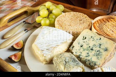 Fromage français - camembert, roquefort, brie, fromage de chèvre et époisse avec raisins et figues gros plan Banque D'Images