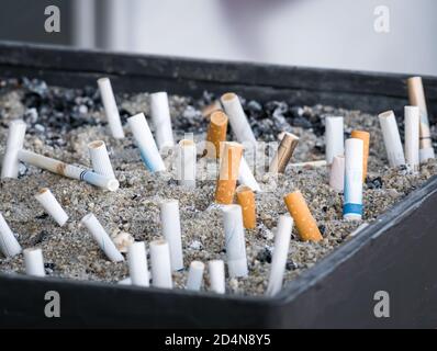 Des mégots de cigarettes dans un cendrier extérieur avec du sable. Banque D'Images