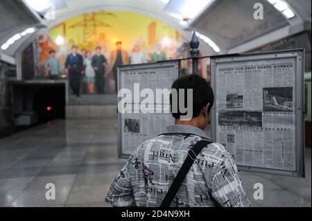 09.08.2012, Pyongyang, Corée du Nord, Asie - UN banlieue lit un journal public en attendant le métro de Pyongyang sur une plateforme de station. Banque D'Images