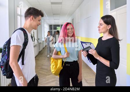 Groupe d'étudiants adolescents parlant à une enseignante dans couloir scolaire Banque D'Images