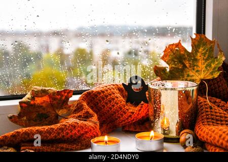 Bougies avec chandail et potiron fantôme, feuilles séchées sur le rebord de la fenêtre. Décoration de la maison d'Halloween. Fenêtre de pluie. Banque D'Images