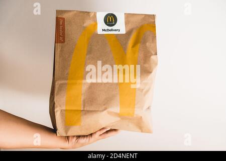Lviv / Ukraine - avril 2020 : manger malsain à la maison pendant l'isolement de la flambée du coronavirus. Main de coursier donnant un sac en papier de McDonalds. Commande Banque D'Images