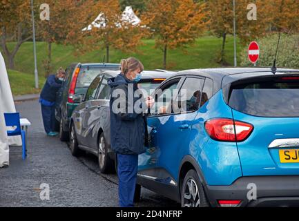 Holyrood High School, Édimbourg, Écosse, Royaume-Uni. 10 octobre 2020. La file d'attente de la grippe provoque le chaos de la circulation alors que des centaines de voitures se garent dans la file d'attente de Duddingston Road West, Le bus local 42 a dû être dirigé au-delà de la ligne de circulation qui s'étend sur toute la longueur de la rue et le tour du coin dans Milton Road West. Cette opération se poursuivra pendant les 4 prochains week-ends, de 9 h à 17 h 30. Photo : membre du personnel se préparant à vacciner un conducteur. Crédit : Arch White/Alamy Live News. Banque D'Images