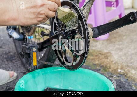 Une personne utilise ensuite une brosse pour nettoyer les engrenages de la bicyclette Banque D'Images