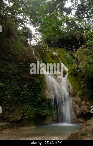 Prise de vue verticale depuis l'eau qui coule du bord de la montagne vers la rivière dans la forêt tropicale Banque D'Images