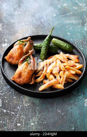 Cailles grillées avec des panais frits ou des pommes de terre et des concombres marinés, foyer sélectif Banque D'Images