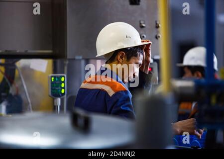 Shymkent, Kazakhstan - avril 26 2012 : usine de production moderne d'huile moteur. Deux ouvriers en casques blancs sur la ligne d'emballage. Banque D'Images