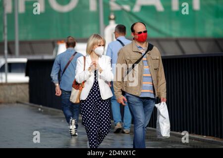 Moscou, Russie, 21 juillet 2020 : un homme et une femme marchent ensemble le long de la rue dans des masques médicaux protecteurs, un homme dans un masque protecteur rouge Banque D'Images