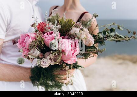 Bouquet de mariage rose avec une pierre rose et pivoines sur le fond de la mer. Banque D'Images