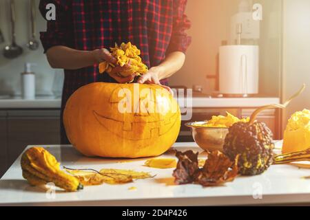 femme préparer la citrouille pour halloween décoration de vacances enlever les graines à cuisine maison Banque D'Images