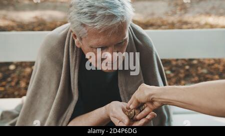 Pauvre homme sans domicile reçoit des pièces de monnaie de voluteer. Photo de haute qualité Banque D'Images