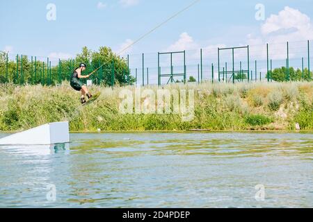 Jeune sportif en casque d'activité et de protection debout sur la planche de surf Banque D'Images