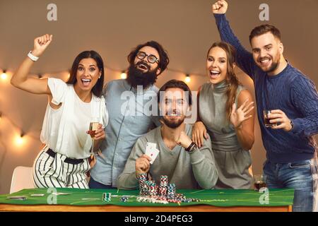 Groupe d'amis enthousiastes célébrant le jeu de poker réussi à fête sur le thème du casino Banque D'Images