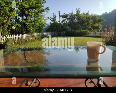 Une tasse de thé ou de café du matin sur une table vue sur une pelouse dans les montagnes Banque D'Images