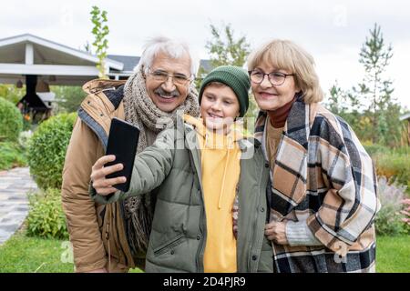 Joyeux écolier qui fait le selfie avec ses grands-parents joyeux et affectueux Banque D'Images