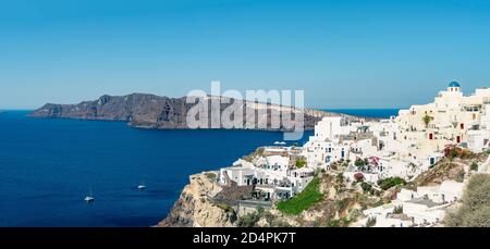 Vue panoramique sur la ville d'Oia sur l'île de Santorin avec d'anciennes maisons blanchies à la chaux et un moulin à vent traditionnel, Grèce. Paysage grec par temps ensoleillé Banque D'Images