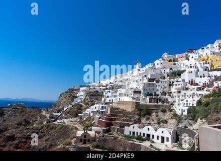 Vue panoramique sur la ville d'Oia sur l'île de Santorini avec d'anciennes maisons blanchies à la chaux et un moulin à vent traditionnel, paysage grec de la Grèce par une journée ensoleillée Banque D'Images