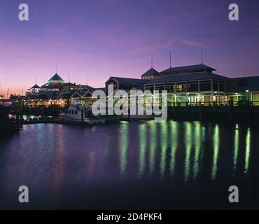 Australie. Queensland. Région de Cairns. Port Douglas. Port de plaisance de Mirage et arcade commerciale au crépuscule. Banque D'Images