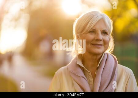 Femme sénior aux couleurs de l'automne au coucher du soleil Banque D'Images