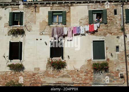 Venise, Italie -septembre 2010 : une femme âgée laisse sécher sa lessive dans l'une des maisons historiques de Venise Banque D'Images
