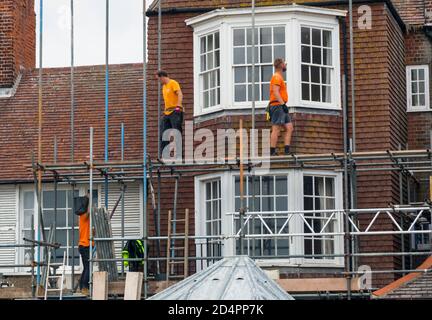 Des hommes au travail érigeant un échafaudage contre une maison. Banque D'Images