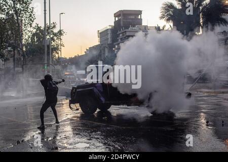 Un manifestant vise un coup de feu vers une voiture blindée pendant la démonstration. Des manifestations et des manifestations ont éclaté le week-end au Chili après que des vidéos aient été filmées montrant un policier des forces spéciales de Carabinero qui a poussé un jeune de 16 ans à descendre du pont Pio Nono à Santiago. Vers la fin de l'après-midi de vendredi, les infirmières techniciens, qui protestent depuis un mois pour une reconnaissance professionnelle, l'amélioration des conditions de travail et l'augmentation des salaires, ont été rejoints par une manifestation spontanée de centaines de jeunes, de groupes autochtones et d'autres groupes sociaux à l'approche d'un référendum pour rejeter le militar Banque D'Images