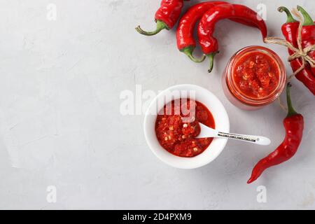 Sauce traditionnelle adjika au piment fort, pâte d'harissa sur fond clair. Orientation horizontale. Vue de dessus Banque D'Images