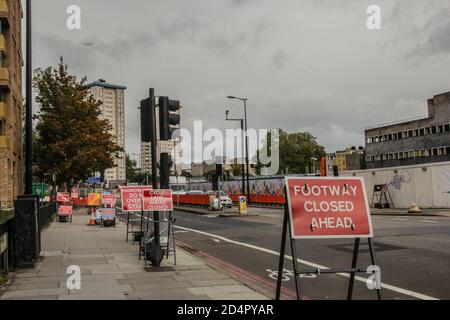 Londres, Royaume-Uni, 10 octobre 2020. Footways fermé et circulation à Hampstead Rd, ville de Londres, en raison des travaux de construction de la ligne de train HS2. Mélèze Maxey, écologiste de longue date et protecteur d'arbres de la rébellion HS2 et de la CAMPAGNE STOP HS2, a grimpé sur le deuxième arbre à gauche - l'un des derniers arbres laissés près du site de construction HS2, il y a quatre jours. Il ne part pas malgré le fait que les travailleurs commencent à couper l'arbre. Banque D'Images