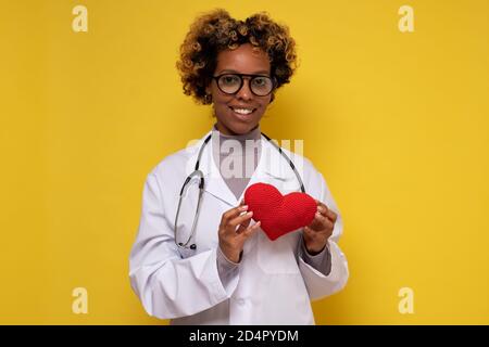 Femme africaine médecin tenant un coeur souriant Banque D'Images