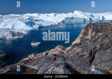 Pêcheurs avec bateau devant de gigantesques icebergs, patrimoine naturel mondial de l'UNESCO, Ilulissat, Disko Bay, West Greenland, Groenland, Amérique du Nord Banque D'Images