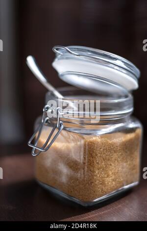 Pot en verre transparent avec canne à sucre brune sur un noir arrière-plan Banque D'Images