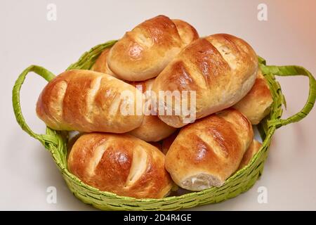 Pain au lait cuit et bruni dans un style traditionnel fait maison, avec beurre et levain, dans un panier en osier sur fond blanc Banque D'Images