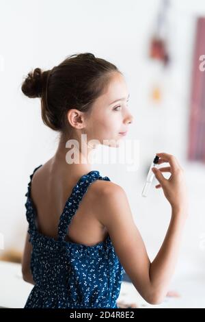 fille de 12 ans appliquant le perfum. Banque D'Images