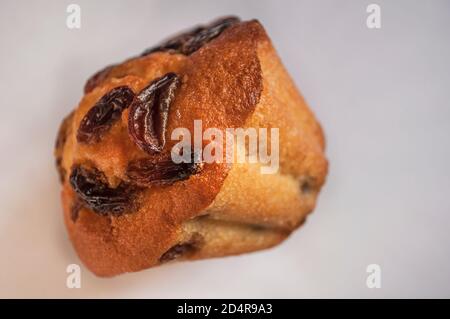 Un cupcake avec des raisins secs couchés sur le côté sur un fond clair, photo en gros plan Banque D'Images