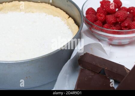Flocons de noix de coco dans un biscuit avec ganache au chocolat. À proximité se trouvent les framboises avec des morceaux de chocolat. Levington gâteau, étapes de préparation. Banque D'Images