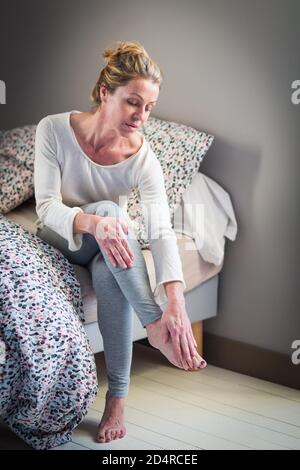 Une femme souffrant de douleurs articulaires dans le pied. Banque D'Images