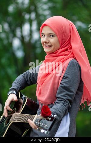 Portrait de la bonne fille musulmane essayant de jouer de la guitare Banque D'Images