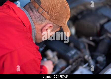 Beau mécanicien d'automobile ou travailleur d'assistance routière en uniforme la réparation de moteur de la voiture cassée sur la route Banque D'Images