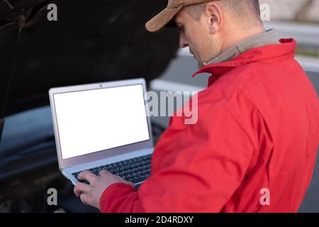 Beau mécanicien d'automobile ou travailleur d'assistance routière en uniforme la réparation de moteur de la voiture cassée sur la route Banque D'Images