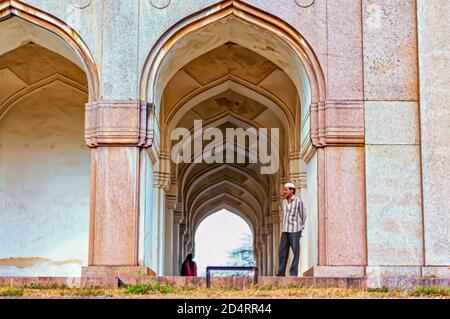 Les visiteurs ont vu se tenir sous les arches/arches à l'intérieur des tombes Qutb Shahi situées à Ibrahim Bagh à Hyderabad, en Inde. Banque D'Images