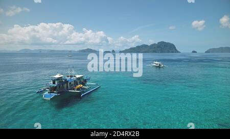 Baie océanique aérienne des Philippines : bateau, bateau à la surface d'eau turquiose. Croisière locale pour touristes à bord de bateau à la baie de mer de l'île El Nido, archipel de Visayas, Asie. Paysage tropical en tir de drone Banque D'Images