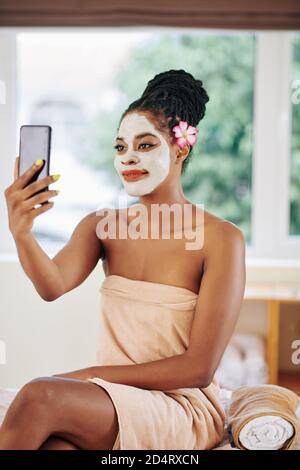Femme avec masque d'argile prenant selfie Banque D'Images