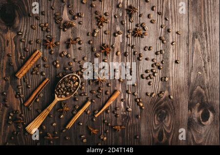Vue de dessus d'une cuillère en bois d'époque, de grains de café, de cannelle et d'anis étoilé sur fond de bois. Banque D'Images