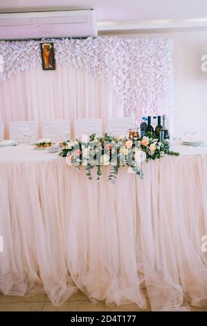 Table de mariage décorée d'un bouquet de roses, d'un eustoma et de feuilles d'eucalyptus. Banque D'Images