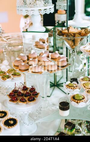 Bar à bonbons pour mariages avec petits gâteaux aux couleurs vives différentes, macarons, gâteaux, gelée et fruits. Banque D'Images