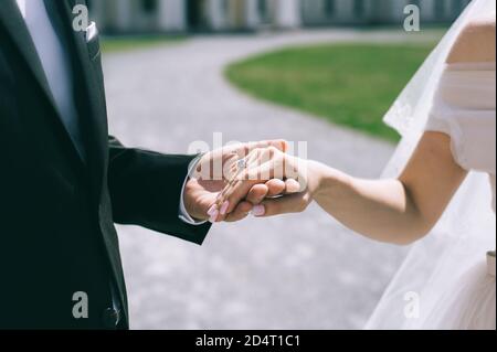 Gros plan d'un couple de mariage tenant les mains à l'extérieur. Arrière-plan flou. Banque D'Images