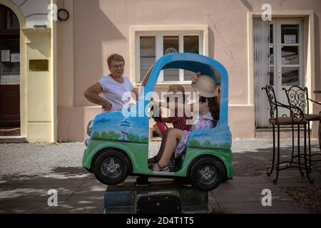 Belgrade, Serbie, 31 août 2020: Grand-mère regardant les petites-filles jouer dans une voiture à cheval jouet Banque D'Images