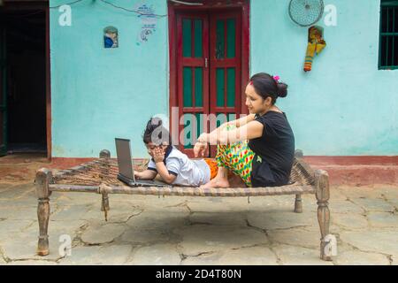 Mère rurale indienne enseignant fille en ligne sur ordinateur portable en utilisant Internet. Utilisation de la technologie dans les villages indiens. Verrouillage et fermeture d'écoles. Banque D'Images